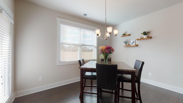 dining area with dark hardwood / wood-style floors and an inviting chandelier