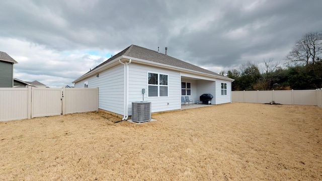 rear view of house with a patio, a yard, and central AC