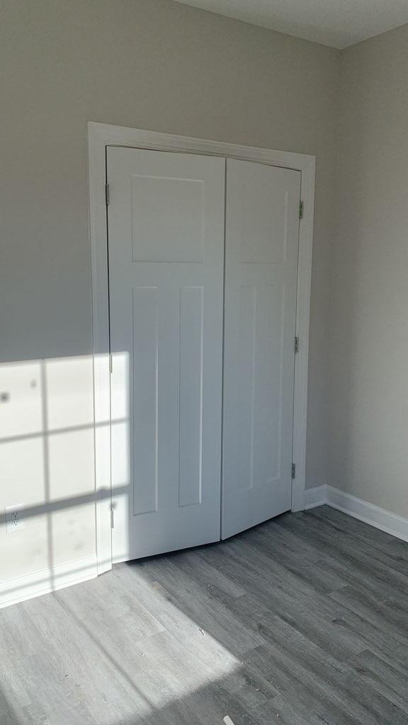 unfurnished bedroom with a closet, baseboards, and wood finished floors