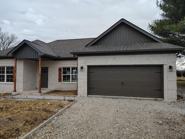 ranch-style home with gravel driveway, roof with shingles, and brick siding