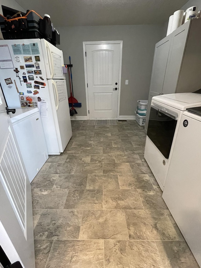 kitchen with white fridge, washer and dryer, and white cabinets