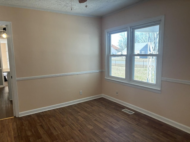 unfurnished room featuring ceiling fan, a healthy amount of sunlight, a textured ceiling, and dark hardwood / wood-style flooring