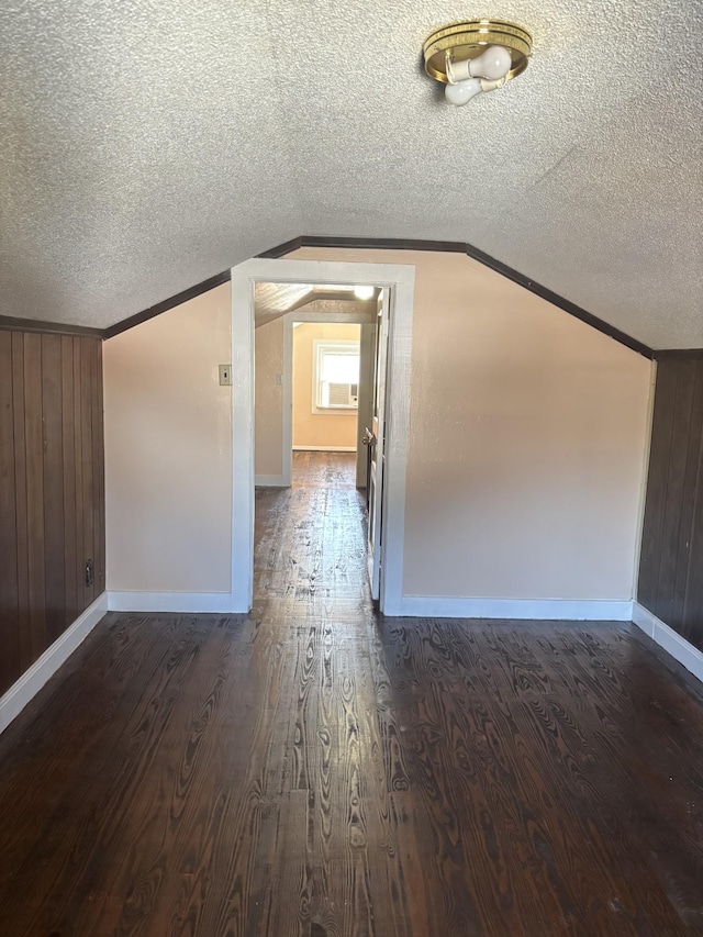 bonus room featuring lofted ceiling, dark wood-type flooring, a textured ceiling, and wood walls