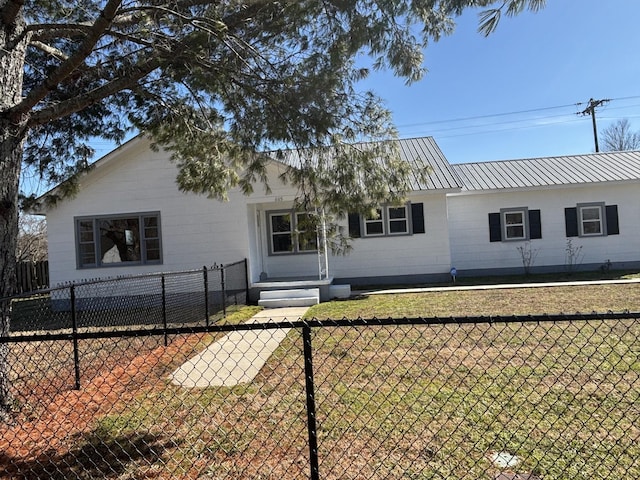 ranch-style house with a front yard, metal roof, and fence