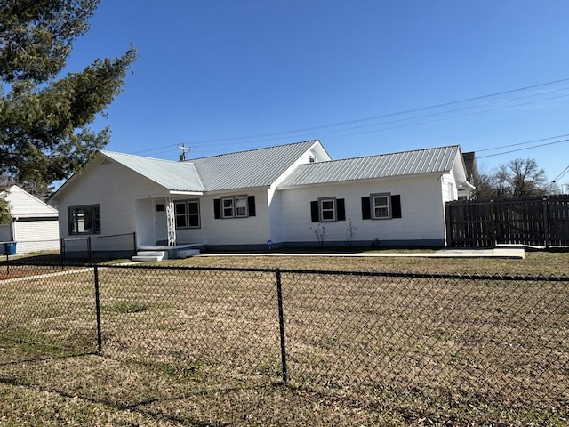 view of front of property with fence private yard, metal roof, and a front yard