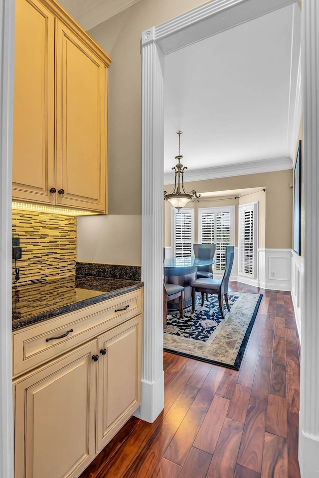 kitchen featuring ornamental molding, dark hardwood / wood-style floors, dark stone countertops, and backsplash