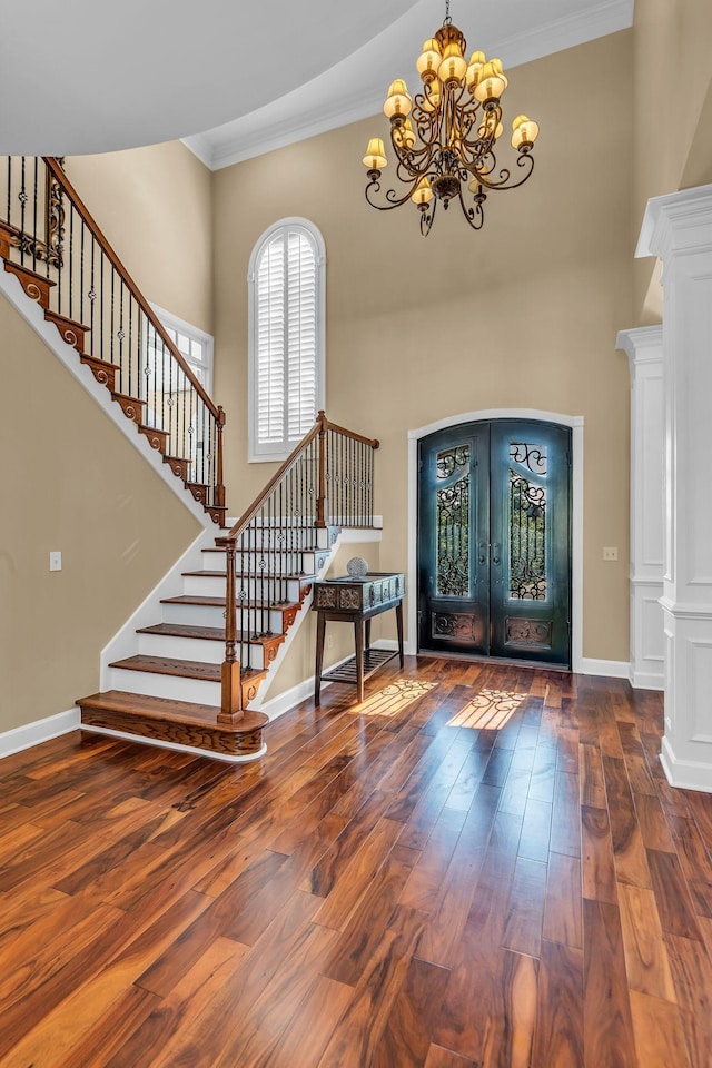 entrance foyer featuring french doors, ornamental molding, dark wood-type flooring, and decorative columns