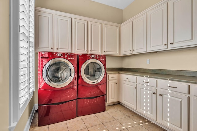 clothes washing area featuring cabinets, washing machine and dryer, and light tile patterned flooring