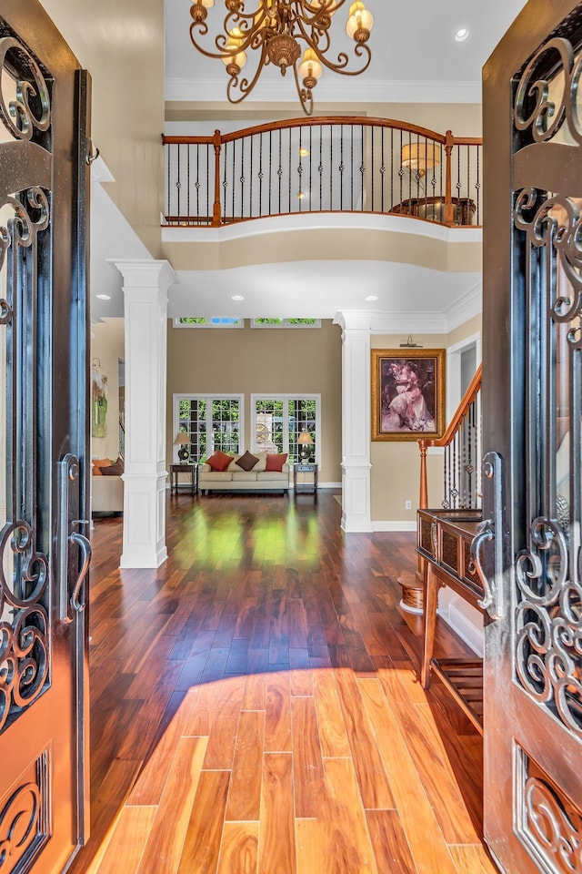 entrance foyer featuring ornate columns, ornamental molding, a towering ceiling, and a chandelier