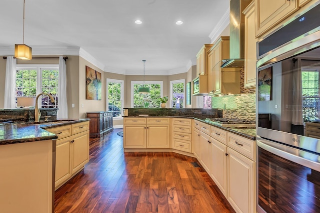 kitchen with dark stone countertops, hanging light fixtures, ornamental molding, and appliances with stainless steel finishes