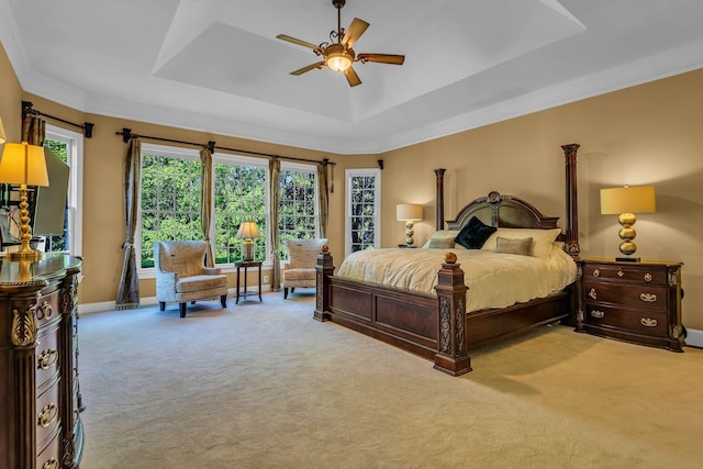 carpeted bedroom featuring crown molding, ceiling fan, and a raised ceiling