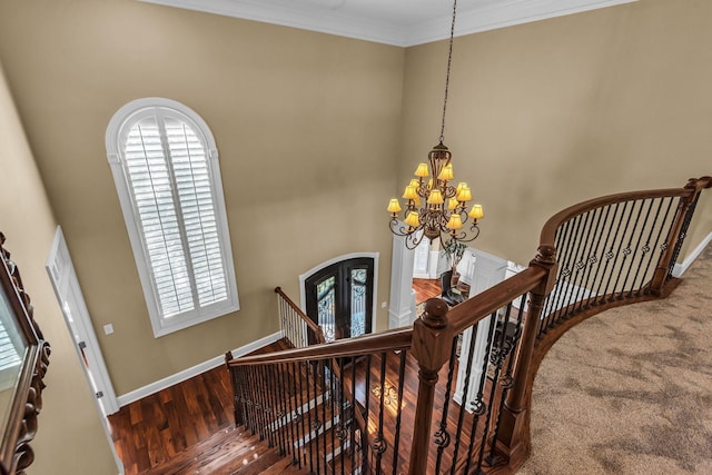 stairs with crown molding, a chandelier, hardwood / wood-style floors, and french doors