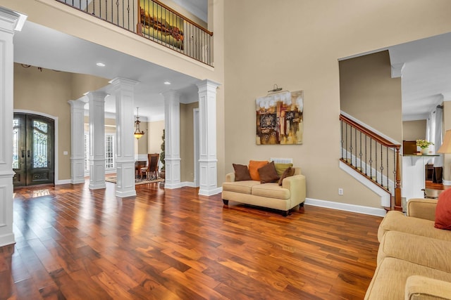 living room with french doors, dark hardwood / wood-style floors, a high ceiling, and ornate columns