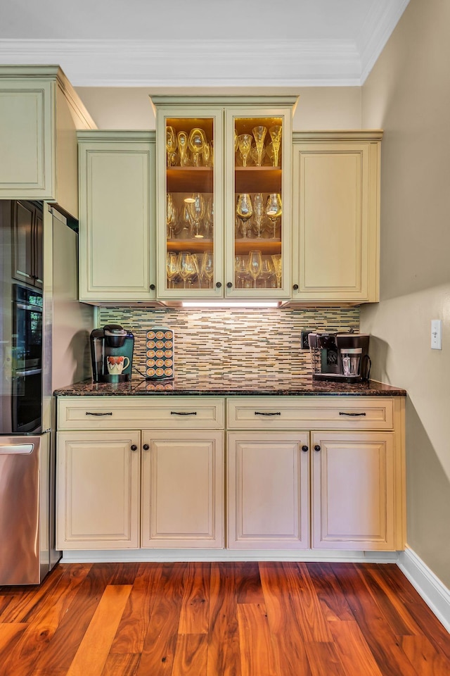 bar featuring dark stone countertops, crown molding, dark hardwood / wood-style floors, and decorative backsplash