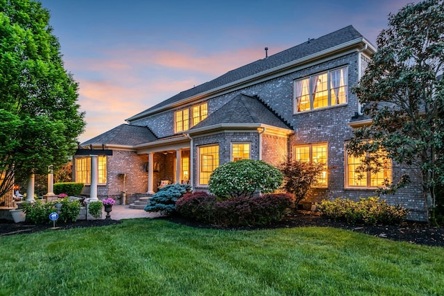 back house at dusk with a lawn