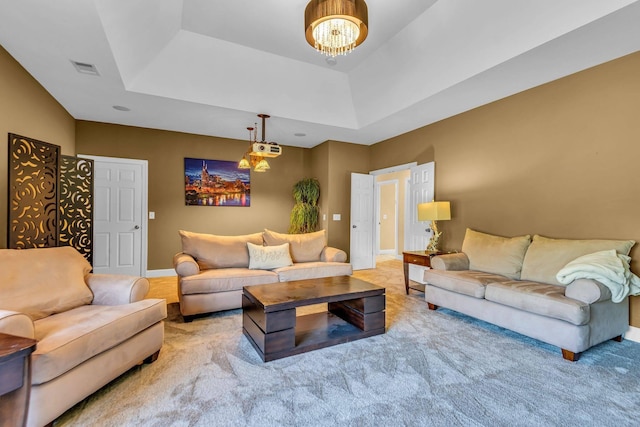 carpeted living room featuring a notable chandelier and a tray ceiling