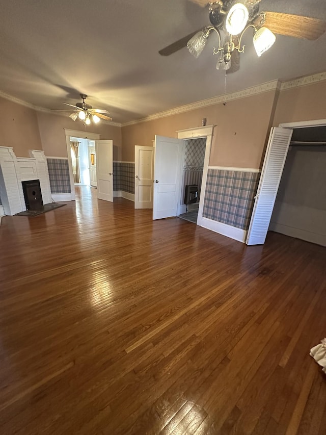 unfurnished living room featuring ceiling fan, ornamental molding, dark hardwood / wood-style floors, and a brick fireplace