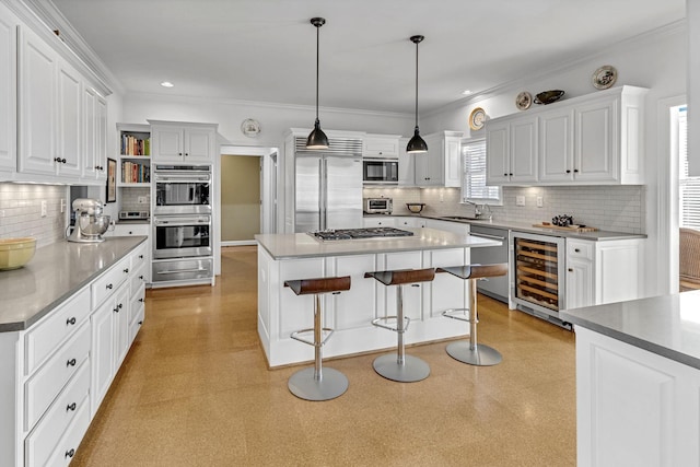 kitchen with pendant lighting, white cabinetry, beverage cooler, a center island, and built in appliances