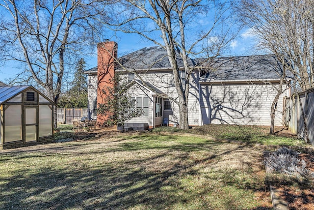 back of property featuring an outdoor structure and a yard