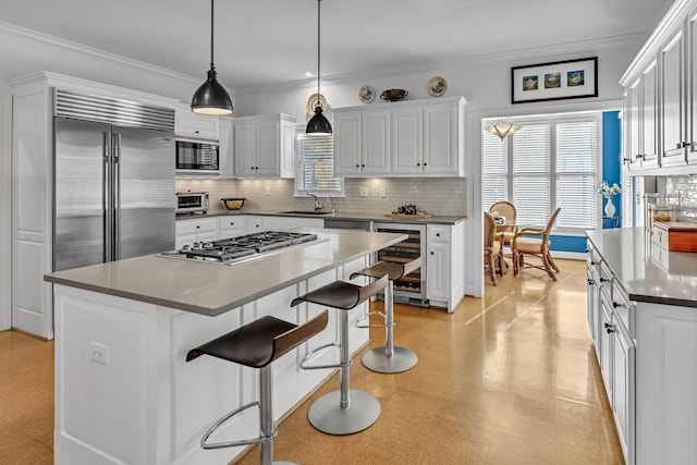 kitchen featuring sink, white cabinetry, built in appliances, a center island, and beverage cooler