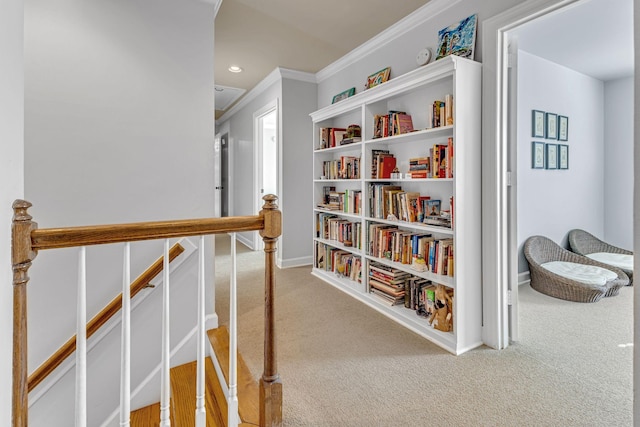 corridor with ornamental molding and light colored carpet