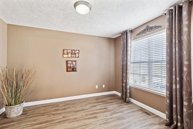 spare room with a textured ceiling and light wood-type flooring