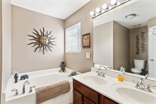 bathroom with vanity, toilet, a textured ceiling, and a tub