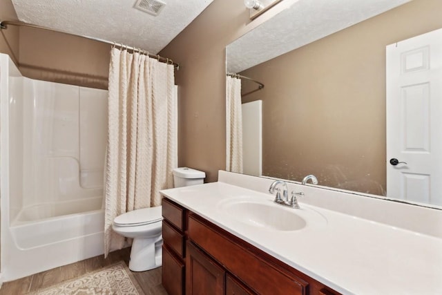 full bathroom featuring hardwood / wood-style floors, vanity, a textured ceiling, toilet, and shower / bath combo with shower curtain