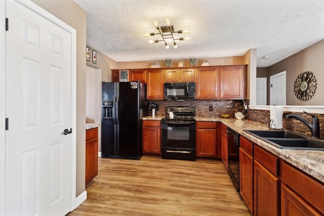 kitchen featuring sink, backsplash, black appliances, light hardwood / wood-style floors, and light stone countertops