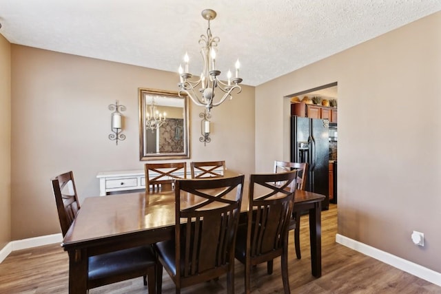 dining area featuring an inviting chandelier, wood-type flooring, and a textured ceiling