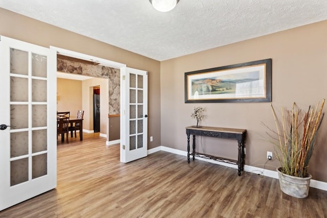 interior space featuring wood-type flooring, french doors, and a textured ceiling