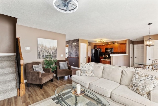 living room featuring hardwood / wood-style flooring, a notable chandelier, and a textured ceiling