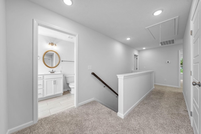 corridor with light colored carpet and sink