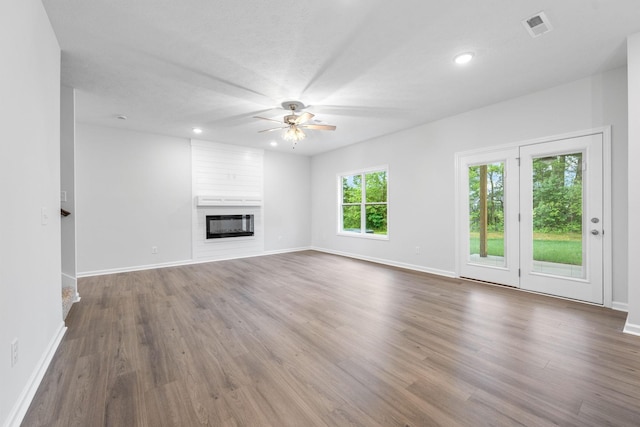 unfurnished living room with dark hardwood / wood-style flooring, a large fireplace, and ceiling fan