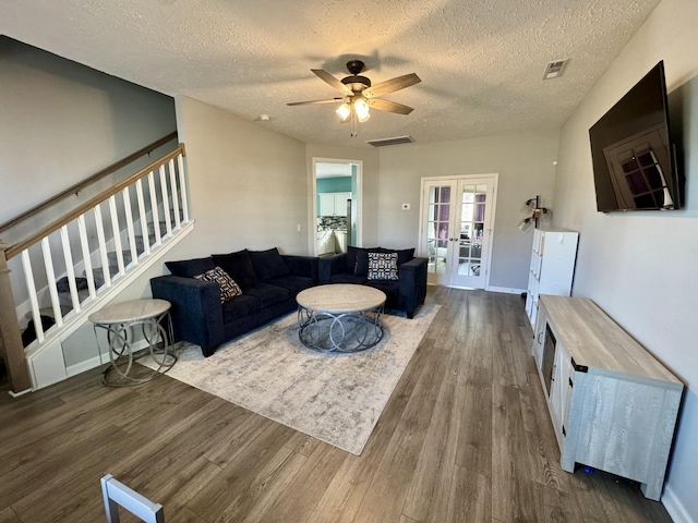 living room featuring french doors, ceiling fan, dark wood-type flooring, and a textured ceiling