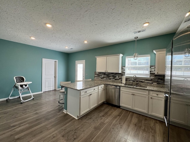 kitchen with hanging light fixtures, dishwasher, sink, and white cabinetry