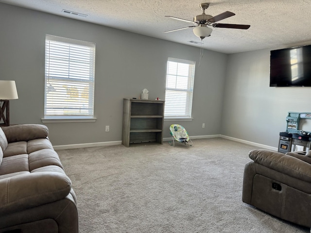 living room with a textured ceiling, light colored carpet, and ceiling fan