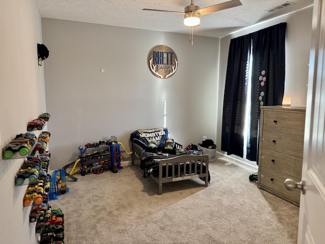 carpeted bedroom with ceiling fan and a textured ceiling