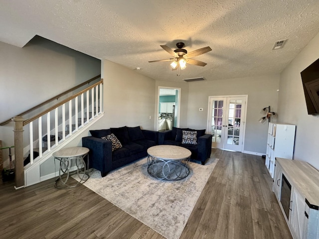 living room featuring french doors, ceiling fan, dark hardwood / wood-style flooring, and a textured ceiling