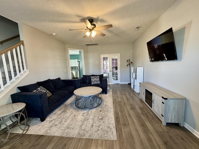 living room featuring french doors, ceiling fan, hardwood / wood-style floors, and a textured ceiling