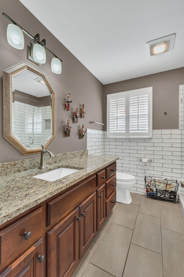 bathroom with tile patterned flooring, vanity, tile walls, and toilet