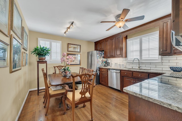kitchen with sink, light stone counters, tasteful backsplash, light hardwood / wood-style flooring, and stainless steel appliances