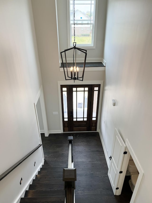 foyer entrance with a towering ceiling, dark hardwood / wood-style floors, and a chandelier