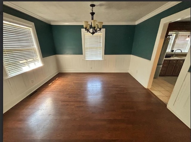 spare room with a notable chandelier, crown molding, a wealth of natural light, and sink