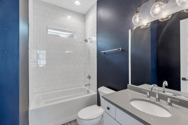 full bathroom featuring vanity, tiled shower / bath combo, and toilet