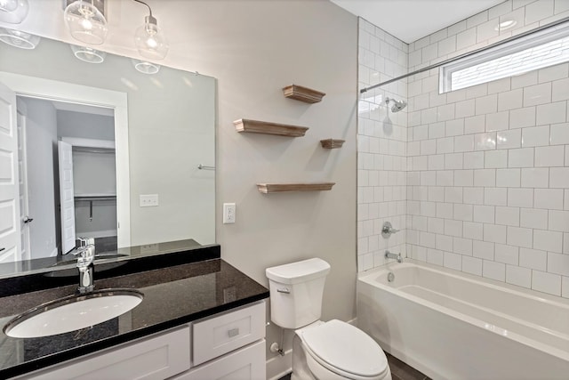 full bathroom with tiled shower / bath, vanity, and toilet