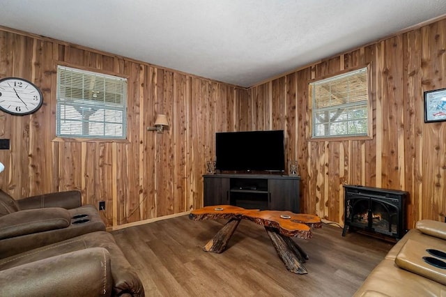 living room featuring wood-type flooring, wood walls, and a wood stove