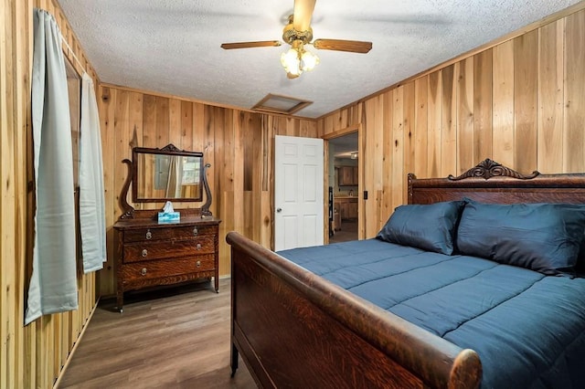 bedroom featuring ceiling fan, hardwood / wood-style floors, a textured ceiling, and wood walls