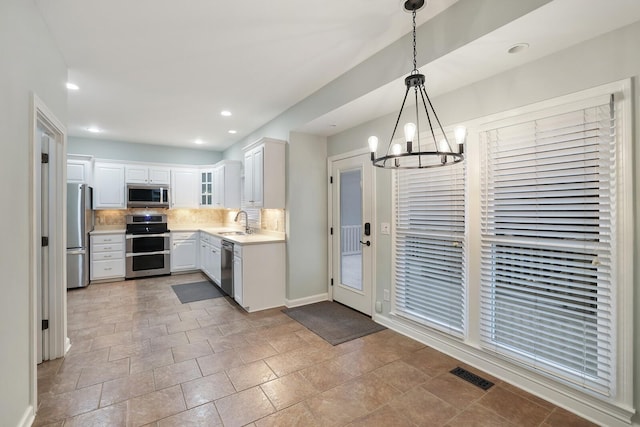 kitchen with sink, white cabinetry, tasteful backsplash, decorative light fixtures, and stainless steel appliances