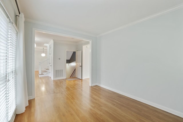 empty room with ornamental molding and light hardwood / wood-style floors